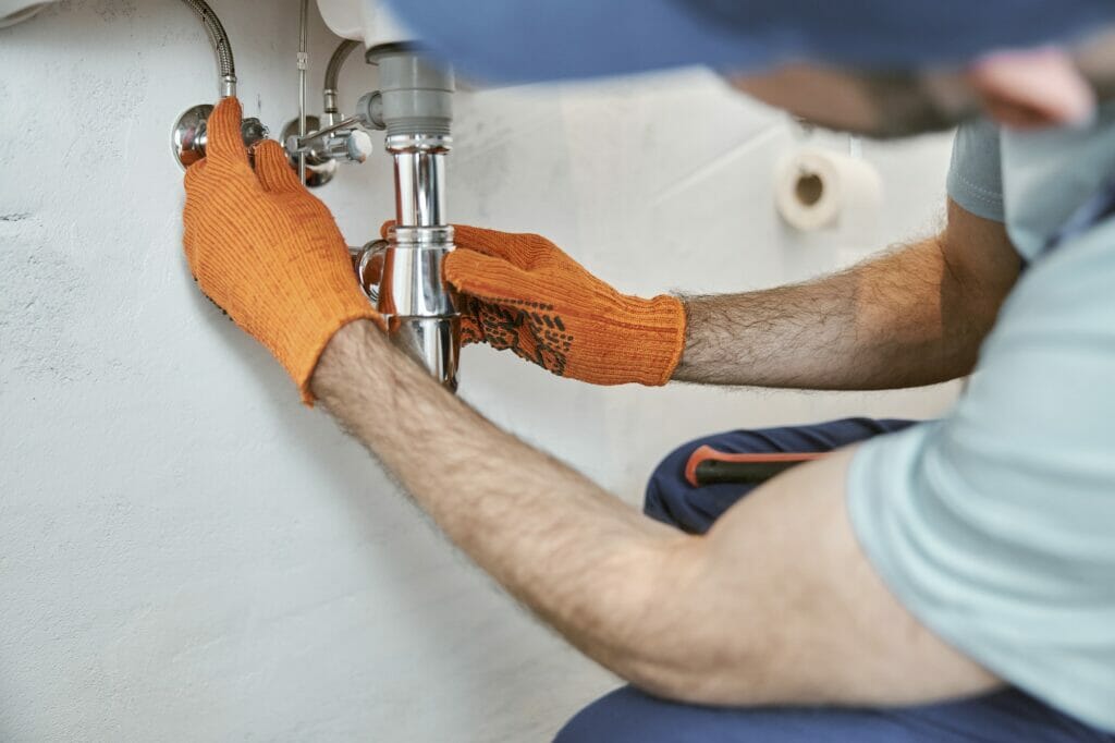 Male plumber hands repairing metal sink pipe
