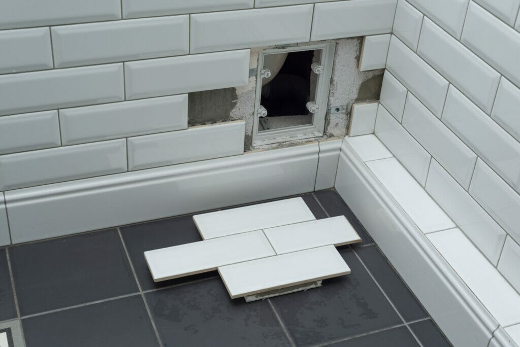 Open hidden revision sanitary hatch on the wall of tile under the bathroom.