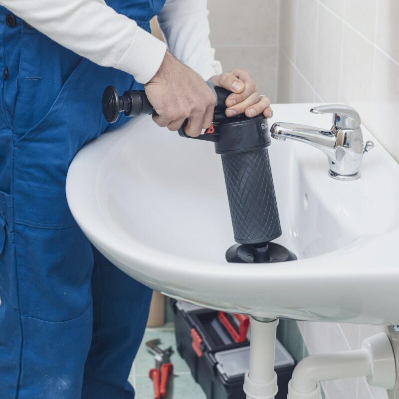 Professional plumber unclogging a sink